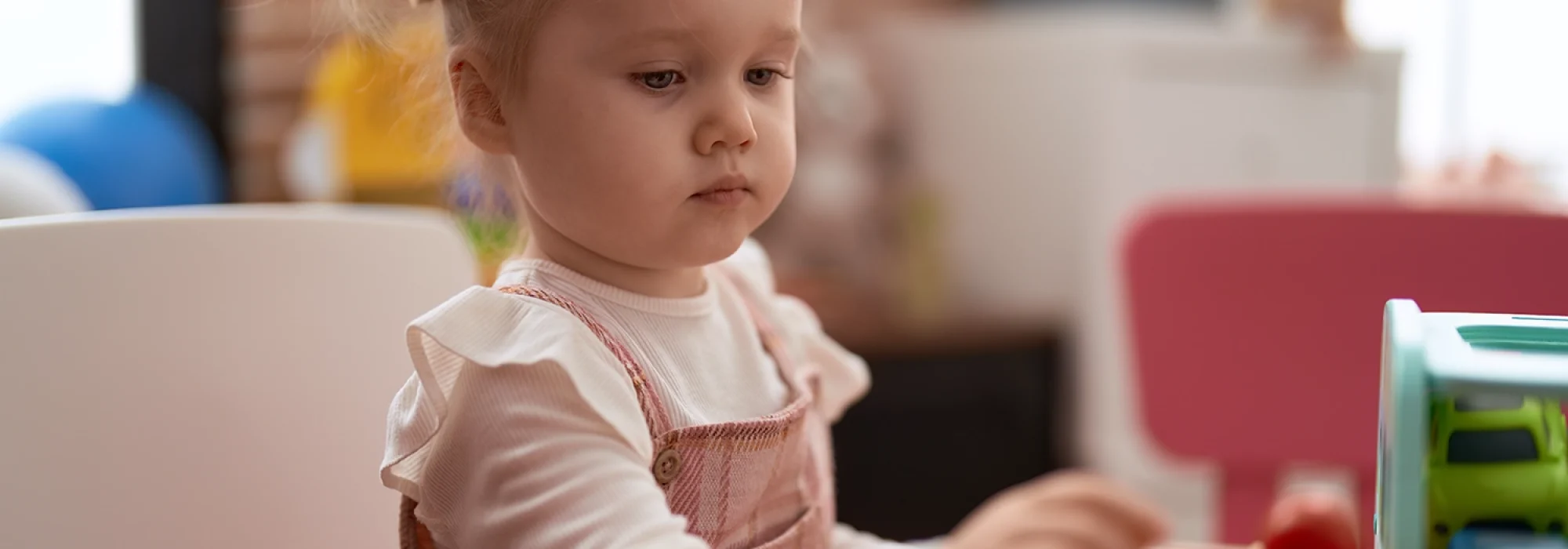 adorable-caucasian-girl-playing-with-toys-sitting-table-kindergarten copia